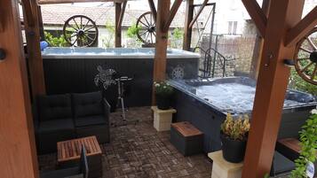 Un patio techado con un jacuzzi, zona de estar y equipo de ejercicios.