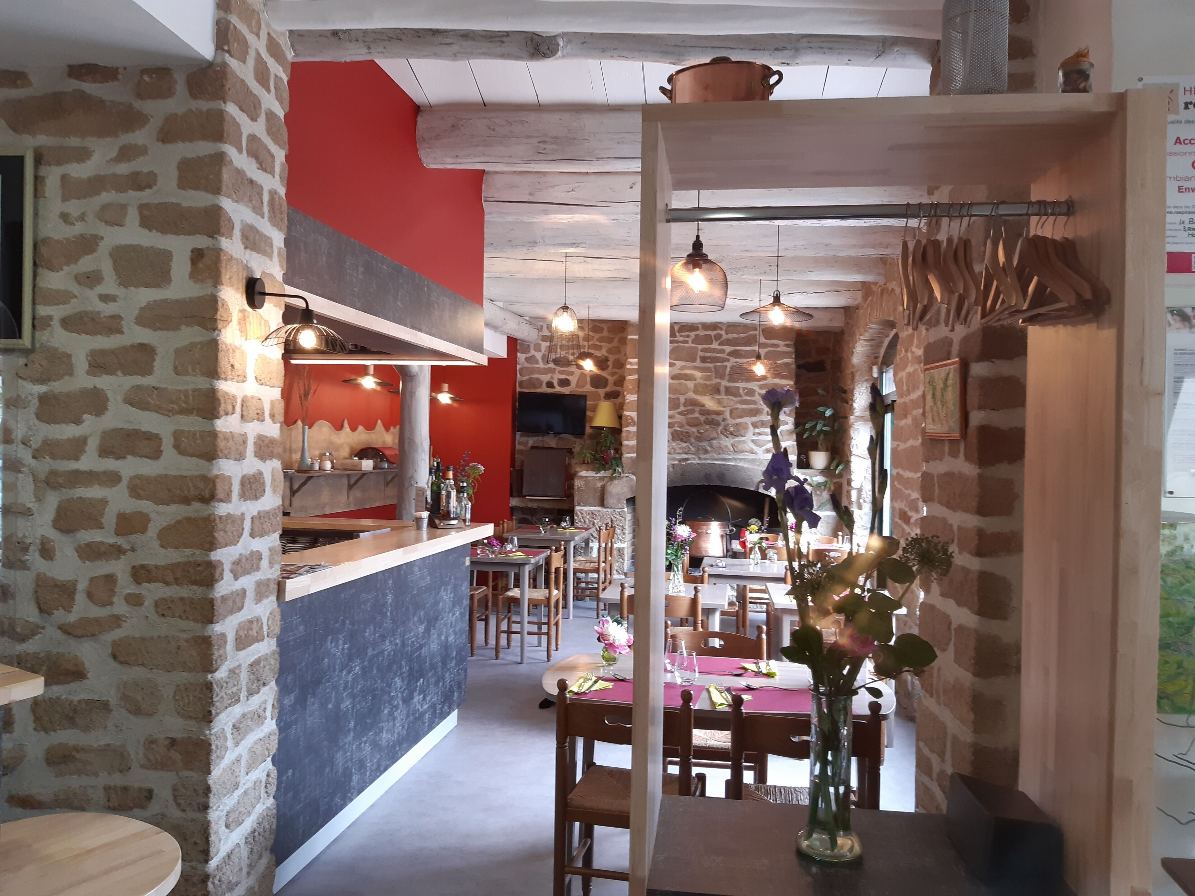 Un interior rústico con paredes de piedra, una barra de madera y una zona de comedor con mesas y sillas.