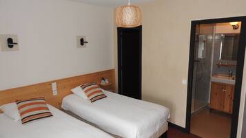A hotel room with two beds, a bathroom with a mirror and sink, and a woven light fixture.