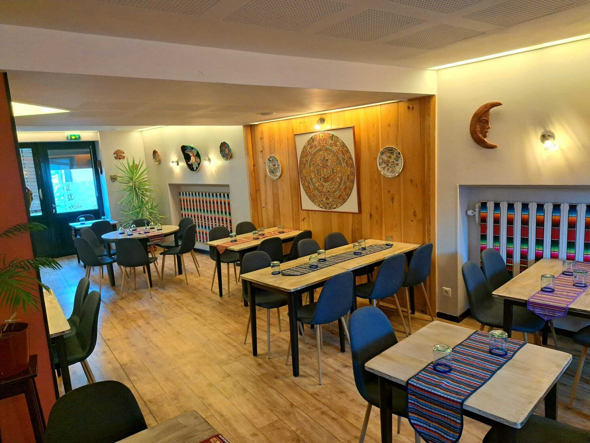 Un restaurante con paredes de madera, un mural grande y mesas con sillas azules.