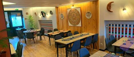 A restaurant with wooden walls, a large mural, and tables with blue chairs.