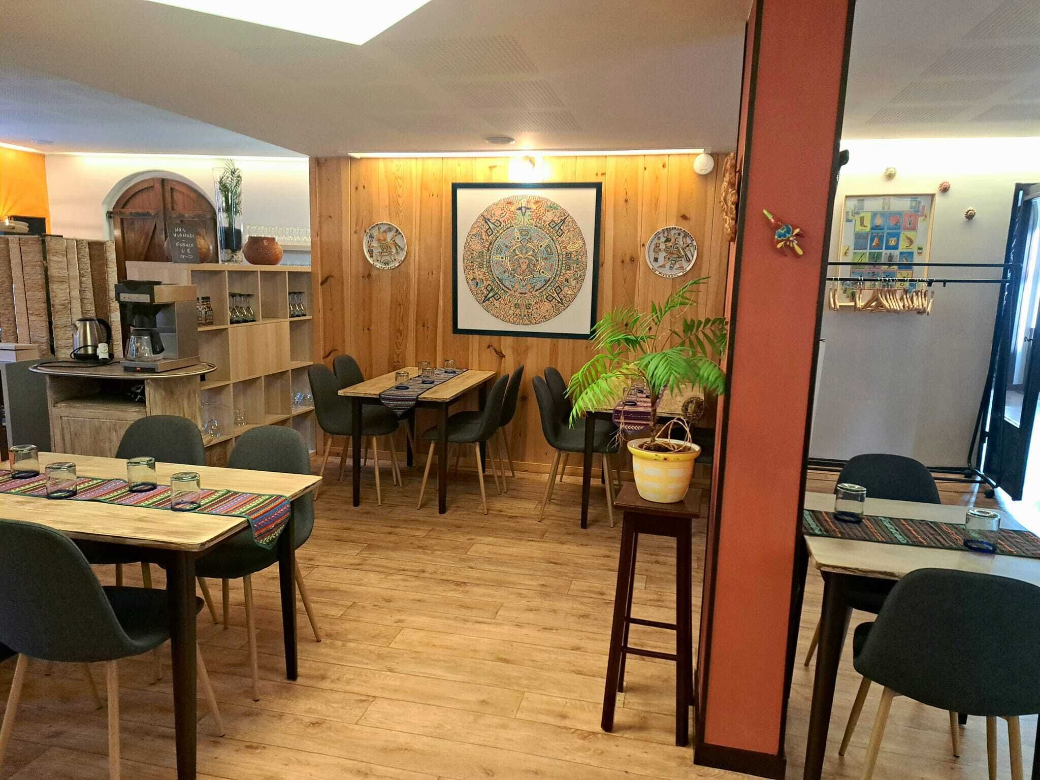 A cozy restaurant with wooden walls, a large decorative wall hanging, and a variety of seating options including tables and chairs.