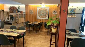 Un restaurante acogedor con paredes de madera, un tapiz decorativo grande y diversas opciones de asientos, incluyendo mesas y sillas.
