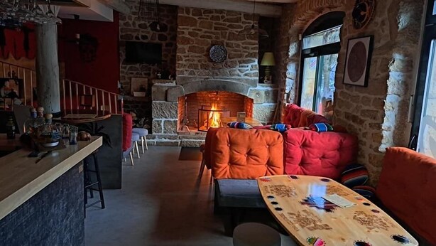 A cozy interior with a stone fireplace, wooden furniture, and a bar area.