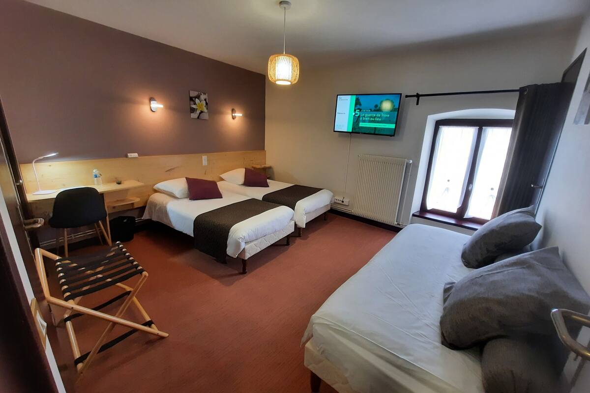 Habitación de hotel con dos camas, un escritorio, una silla, un televisor y una ventana.