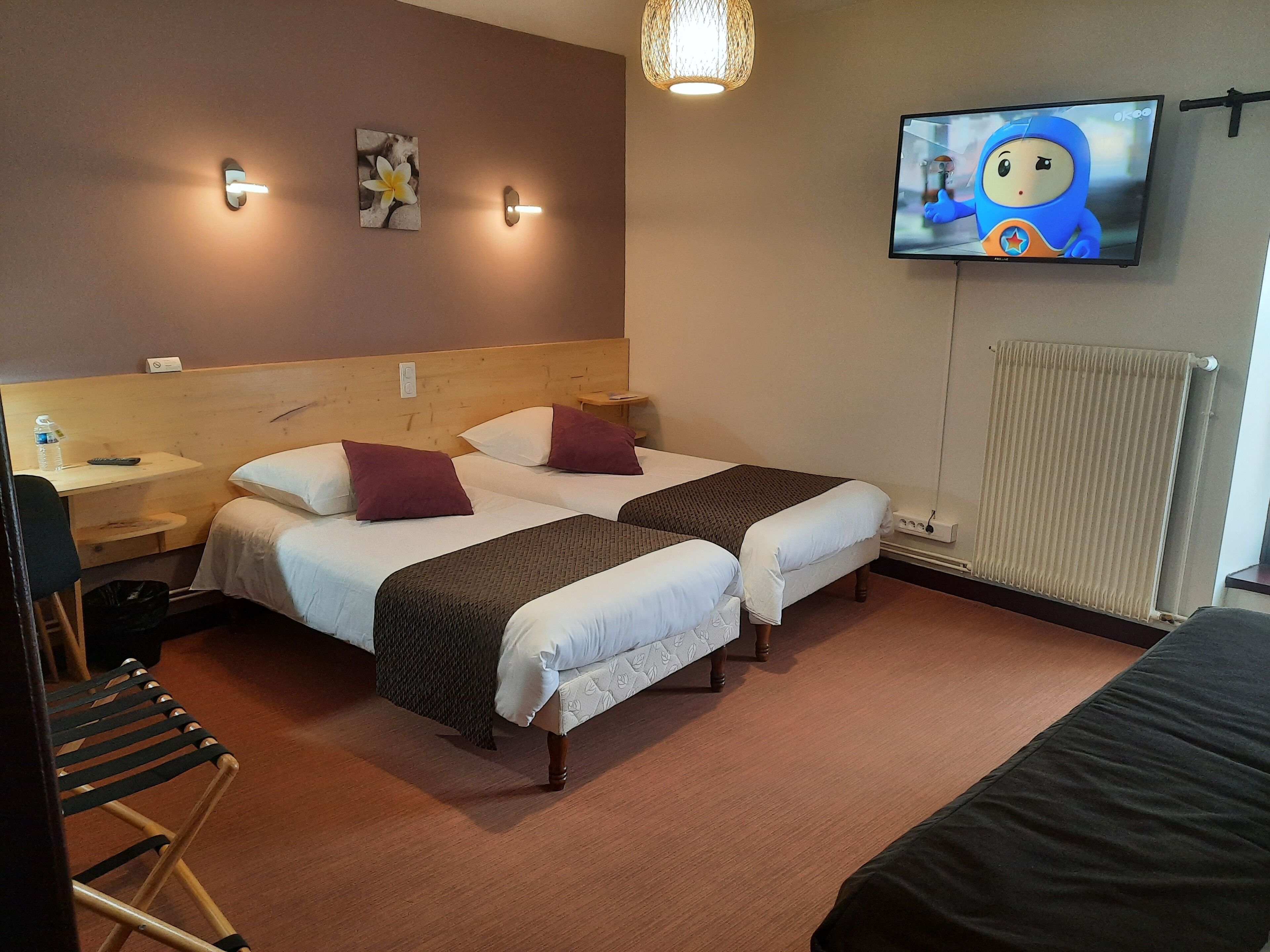 A hotel room with two beds, a TV, a desk, and a chair.