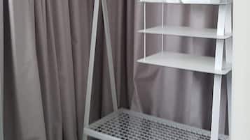 A white metal shelf unit with a hanging rack and shelves, placed against a grey curtain backdrop.