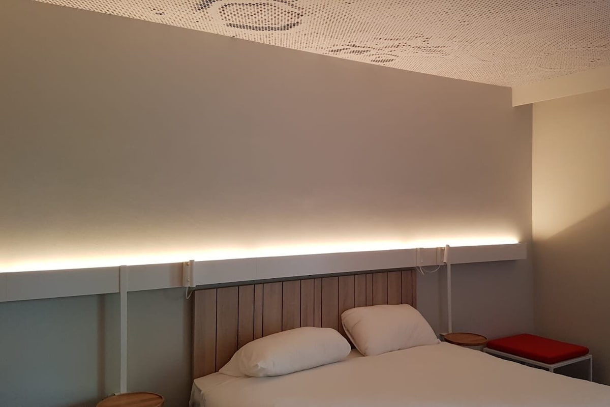 A bedroom with a bed, a bedside table, and a red chair.