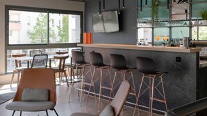 Un bar moderne doté d’un long comptoir, de nombreux tabourets et d’une grande fenêtre offrant une vue sur l’extérieur.