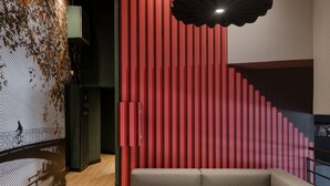 Ein modernes Interieur mit einer Eckcouch, einem Couchtisch mit Zeitschriften, einem gemusterten Teppich und einem außergewöhnlichen Deckendesign.