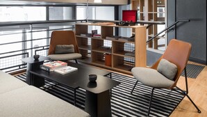 Ein stilvoller Lounge-Bereich mit einer Couch, Sesseln, einem Couchtisch und einem Bücherregal.