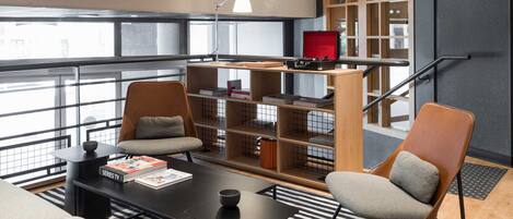 A modern lounge area with a sofa, chairs, a coffee table, and a bookshelf.
