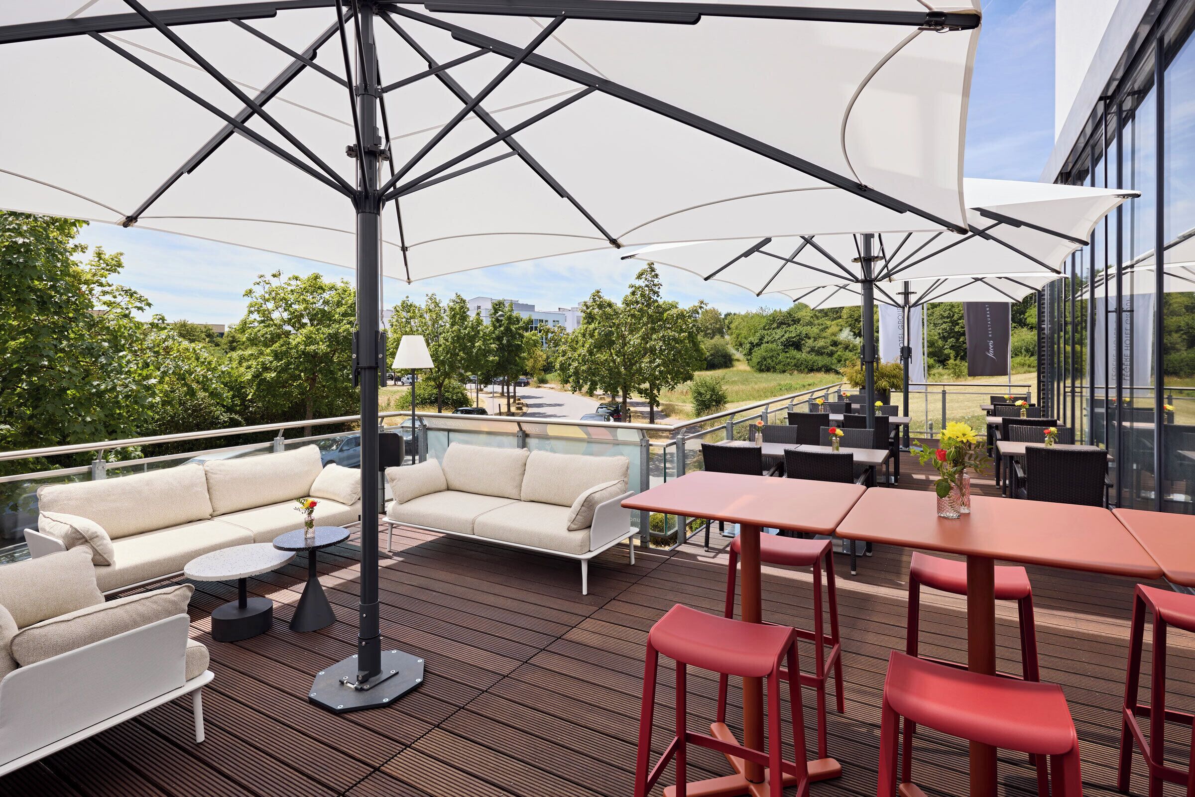 Une terrasse extérieure avec un canapé, des tables et des chaises, une rambarde et une vue sur les environs.