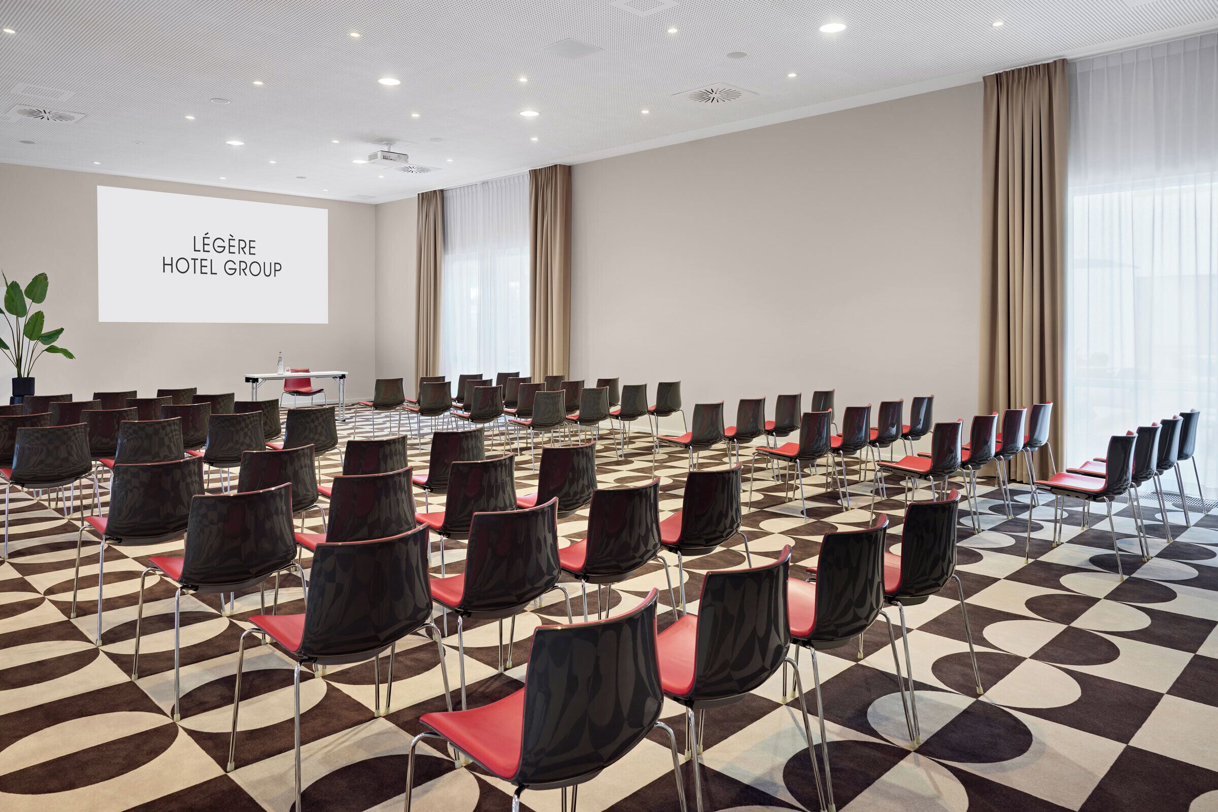 A conference room with rows of chairs, a projector screen, and a checkered floor pattern.