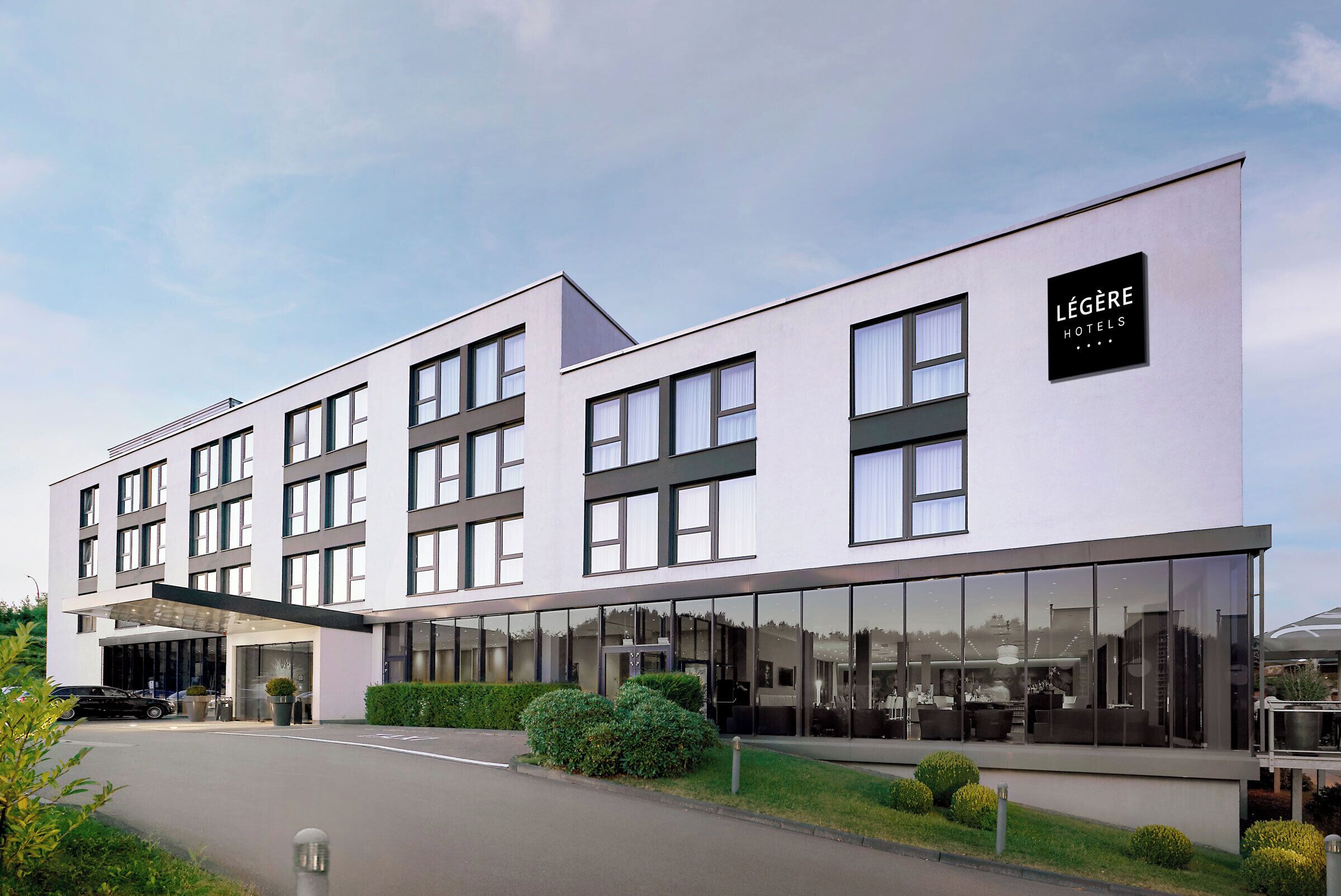 A modern hotel building with a flat facade, large windows, and a sign indicating it's a hotel.