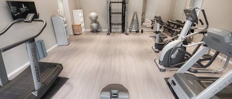 A modern gym with cardio machines, free weights, and a squat rack.