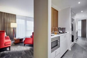 A modern hotel room with a dining area, a kitchen, and a living space.