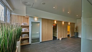 Un moderno vestíbulo de hotel con un amplio espacio abierto, una recepción y una puerta de cristal que da a las habitaciones.