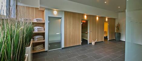 A modern hotel lobby with a large open space, a reception desk, and a glass door leading to the rooms.