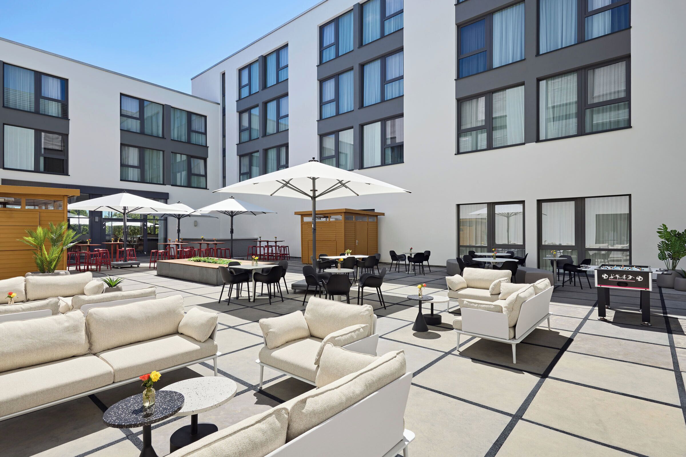 A rooftop patio with outdoor seating, tables, and umbrellas.