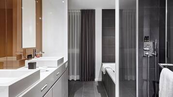 A modern bathroom with a large mirror, two sinks, a shower, and a toilet.