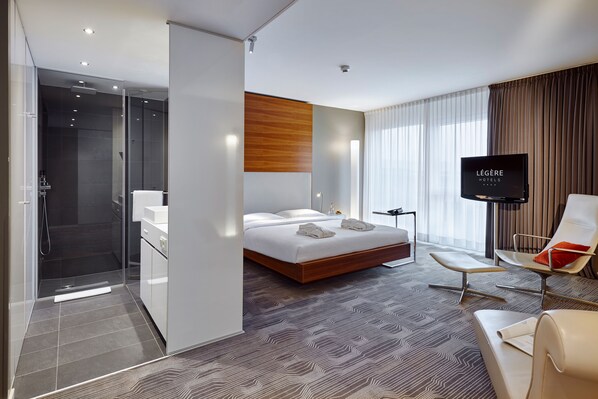 Une chambre d’h ôtel moderne dotée d’un grand lit, d’une télévision, d’un coin salon et d’une douche.