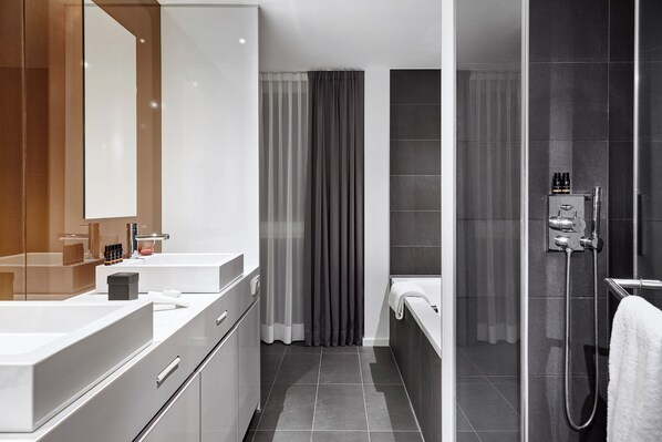 A modern bathroom with a large mirror, two sinks, a shower, and a toilet. - LEGERE HOTEL Luxembourg (Schuttrange)