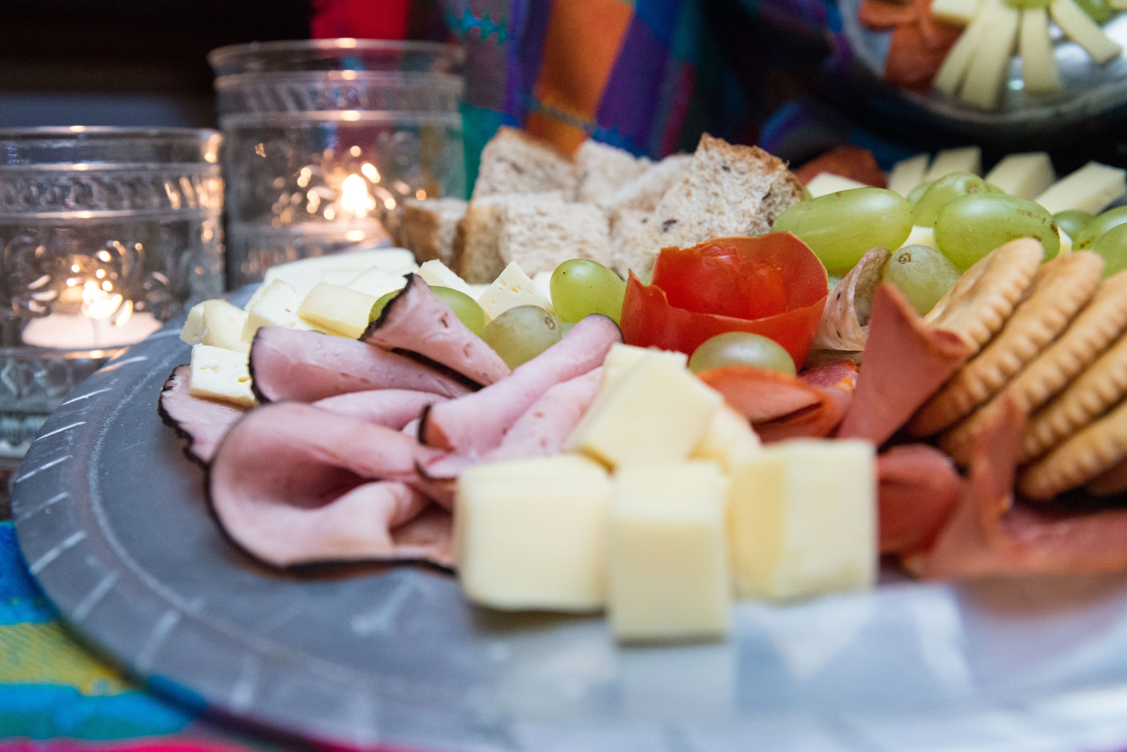 Een charcuteriebord met verschillende kazen, vleessoorten en fruit.