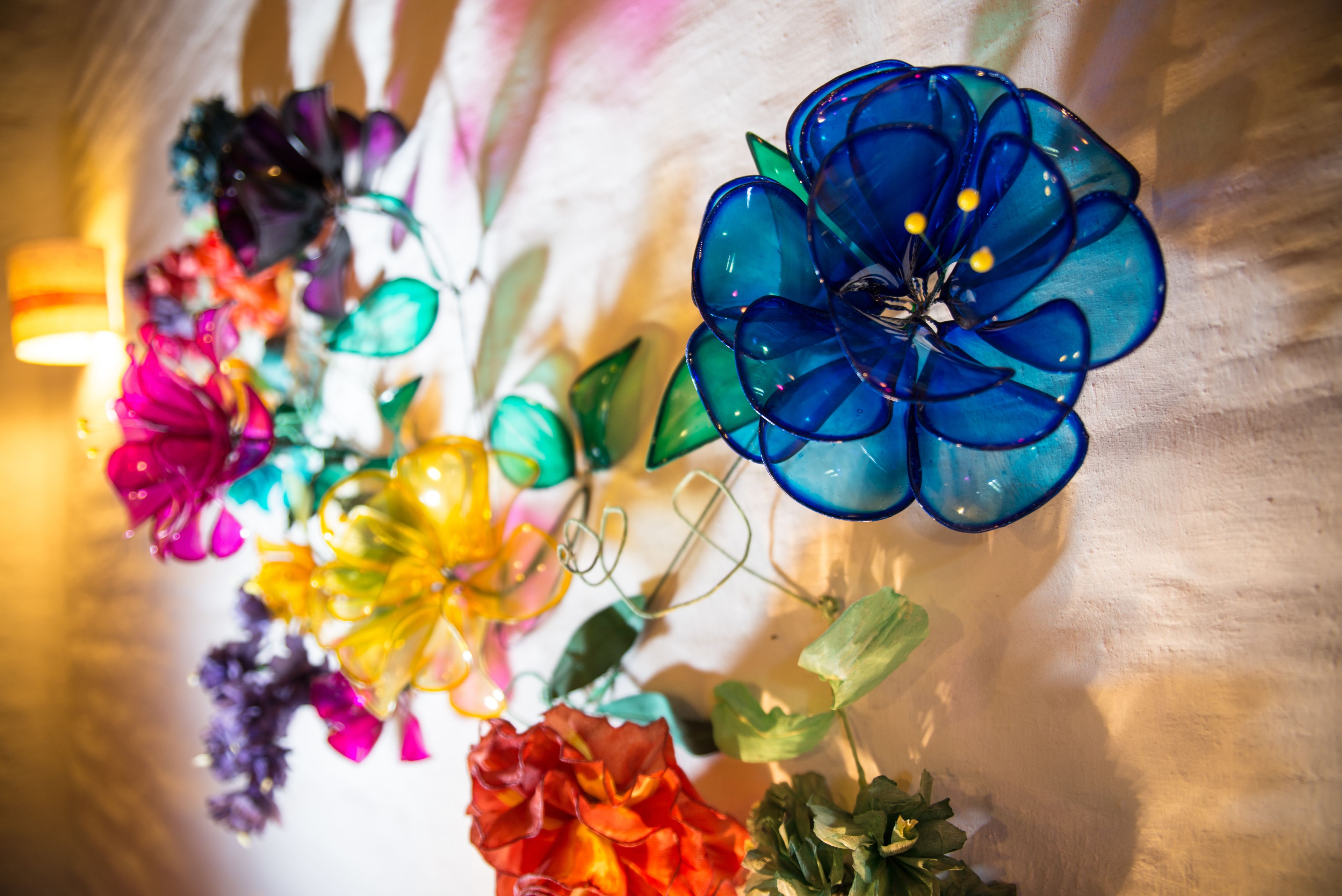 Una variedad de flores de vidrio coloridas expuestas sobre una pared con textura.