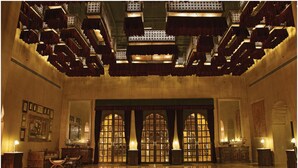 A grand lobby with ornate chandeliers, large arched windows, and a classic wooden reception desk. - Suryagarh (Jaisalmer)