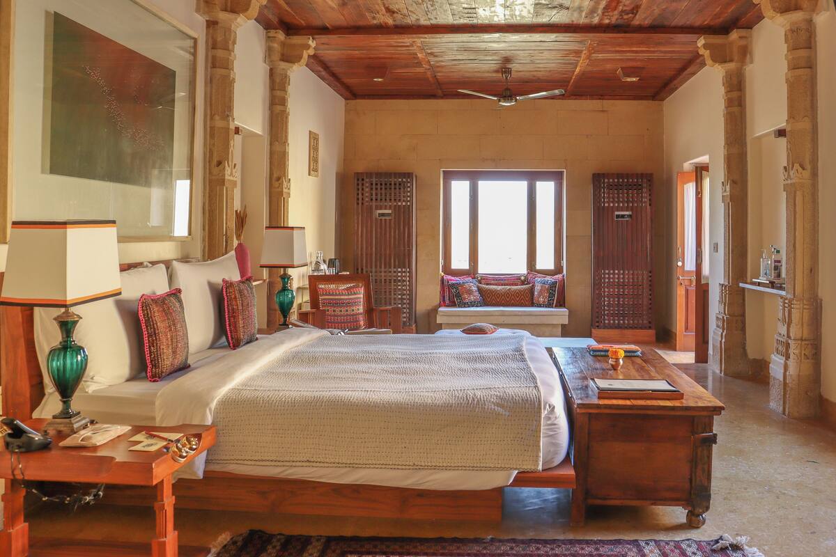Un dormitorio amplio con una cama grande, techo de madera y vistas al exterior a través de una ventana.