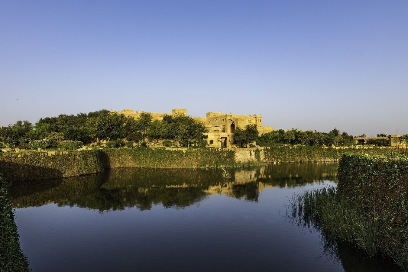 A historic fort with a moat and reflection in the water.