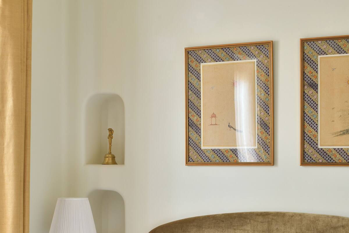 Una habitación de hotel con una cama, una mesita de noche con una lámpara, un teléfono y cuadros en la pared.