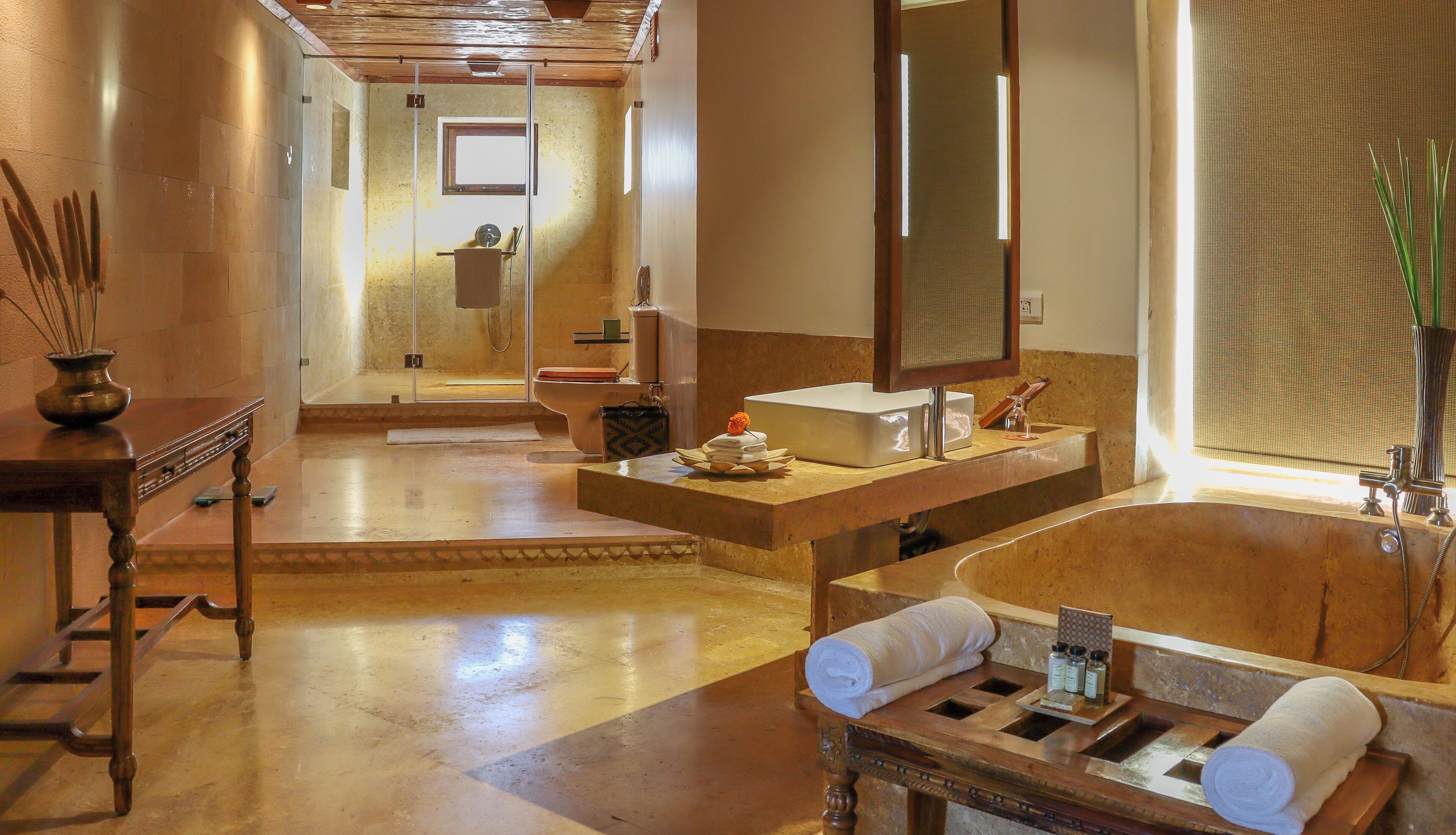A spacious bathroom with a large bathtub, a wooden vanity, a mirror, and a shower area.