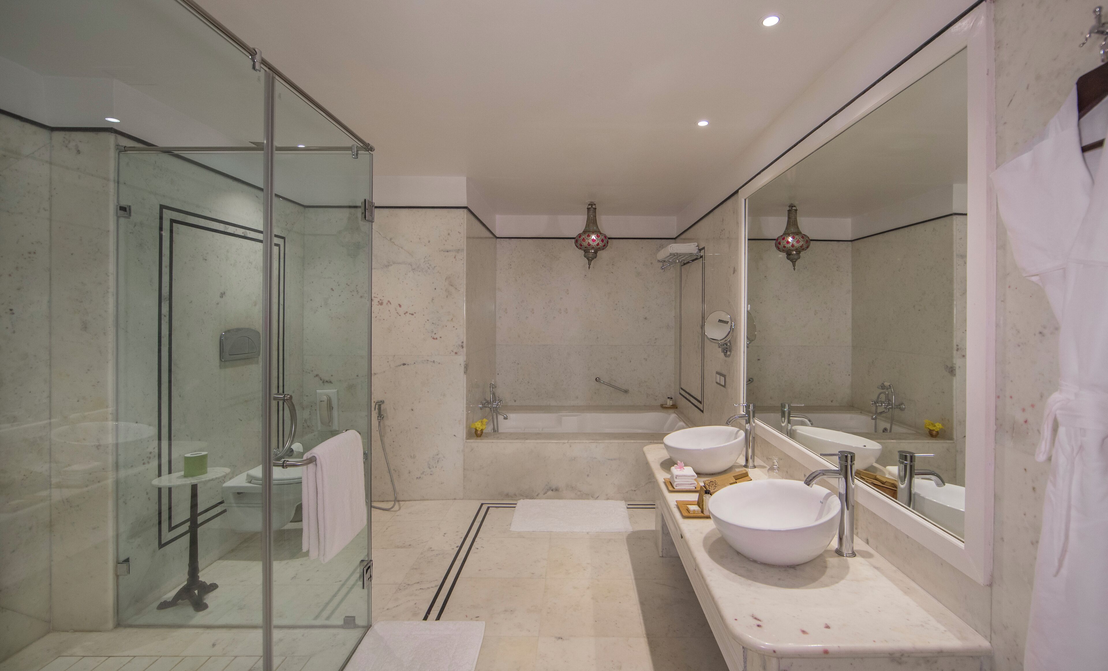 A modern bathroom with a glass-enclosed shower, two sinks, and a large mirror.