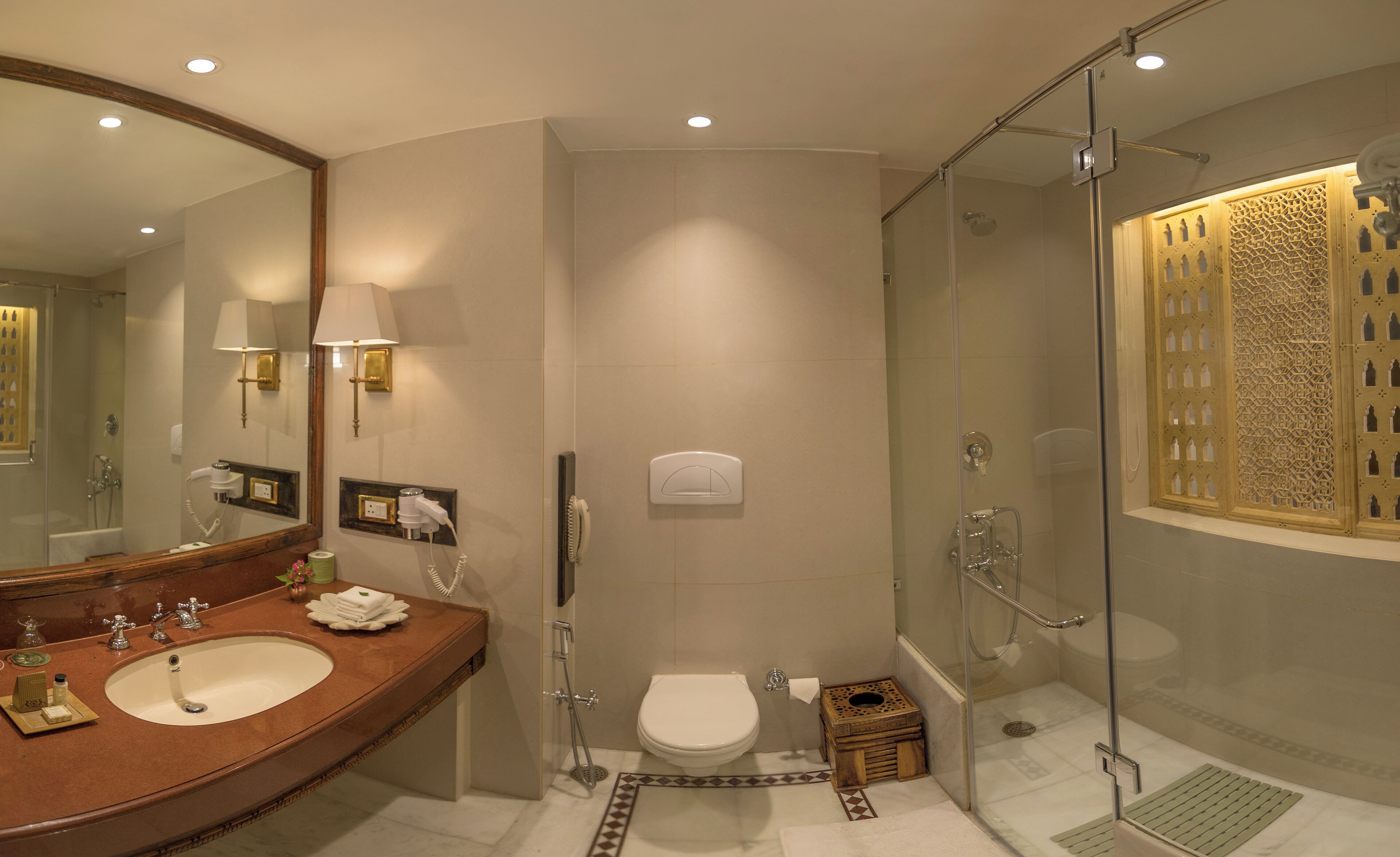 A modern bathroom with a large mirror, dual sinks, a toilet, and a glass-enclosed shower.