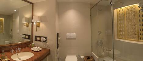 A modern bathroom with a large mirror, dual sinks, a toilet, and a glass-enclosed shower.
