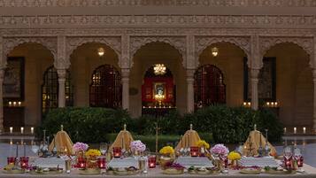 A banquet table set up in a grand hall with ornate arches and a central chandelier.