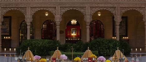 A banquet table set up in a grand hall with ornate arches and a central chandelier.
