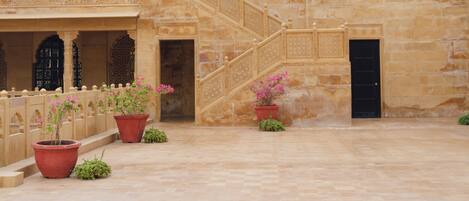 A courtyard with a stone staircase, potted plants, and a traditional building facade.