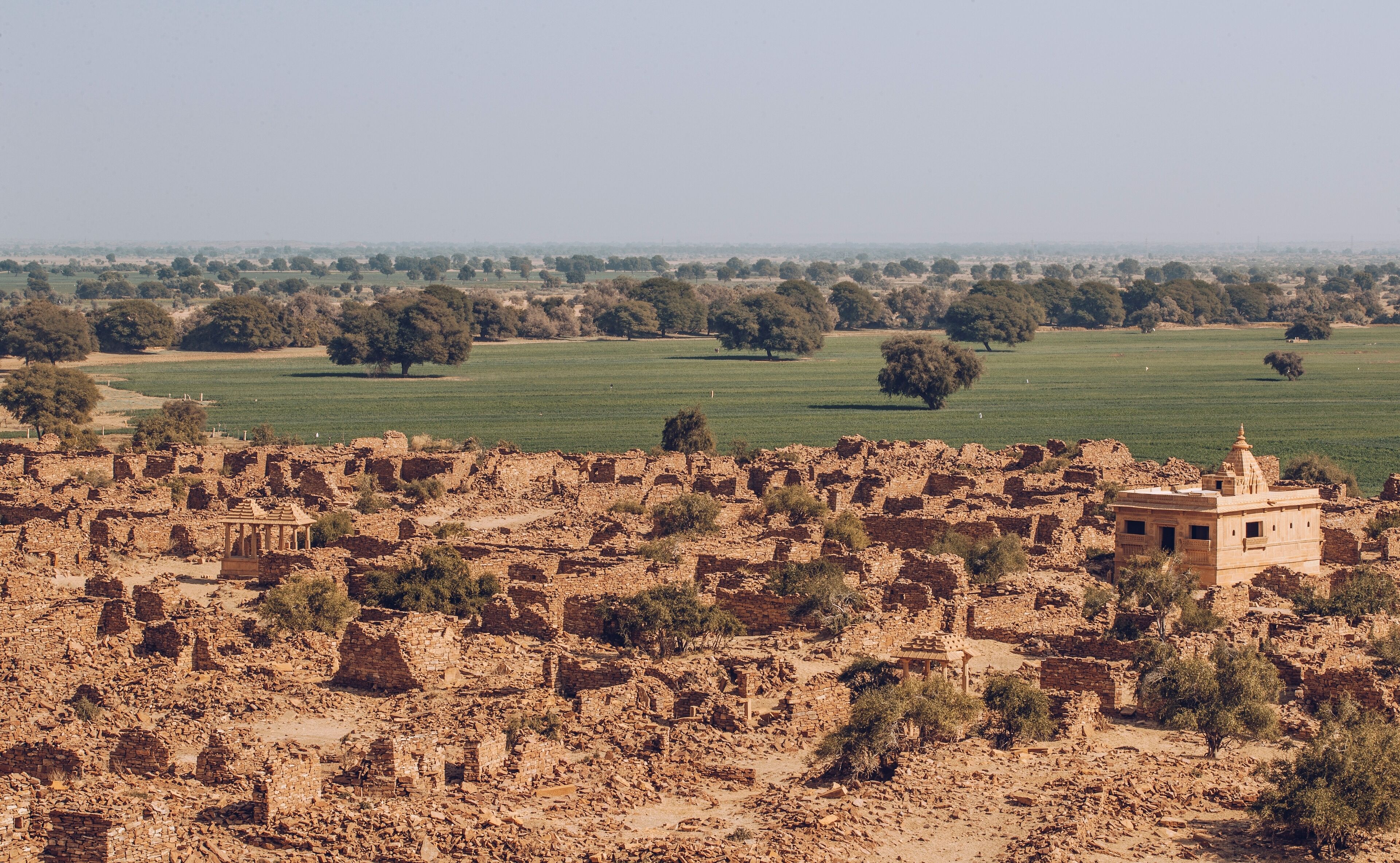 Eine alte Ruine mit verstreuten Gebäuderesten und weiter Aussicht auf die umliegende Landschaft.