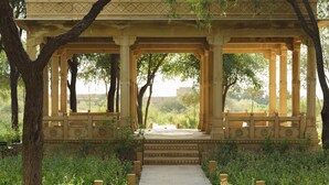 A traditional pavilion with a central pathway leading to a seating area, surrounded by lush greenery. - Suryagarh (Jaisalmer)