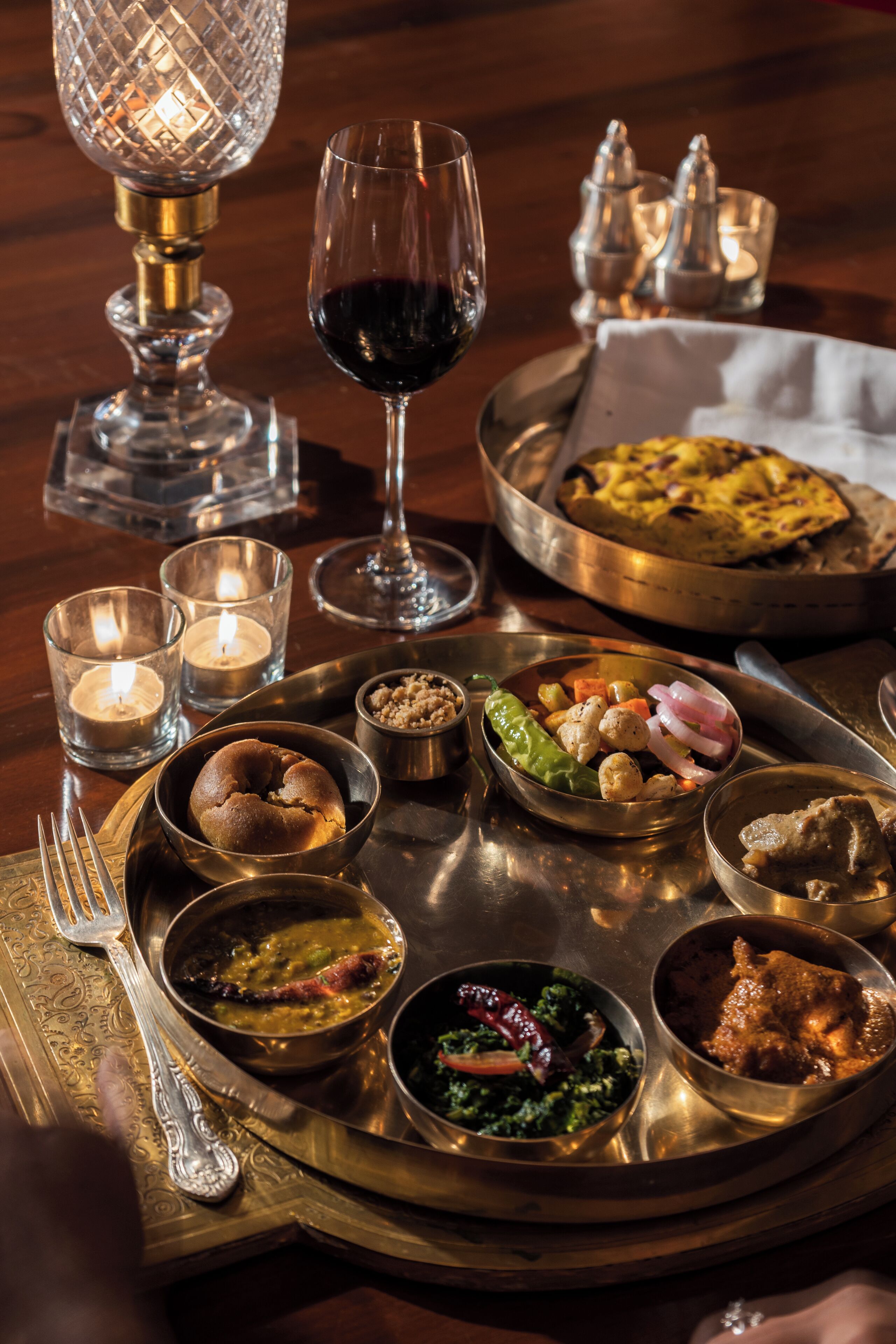 A dining table with various dishes, a wine glass, and candles.