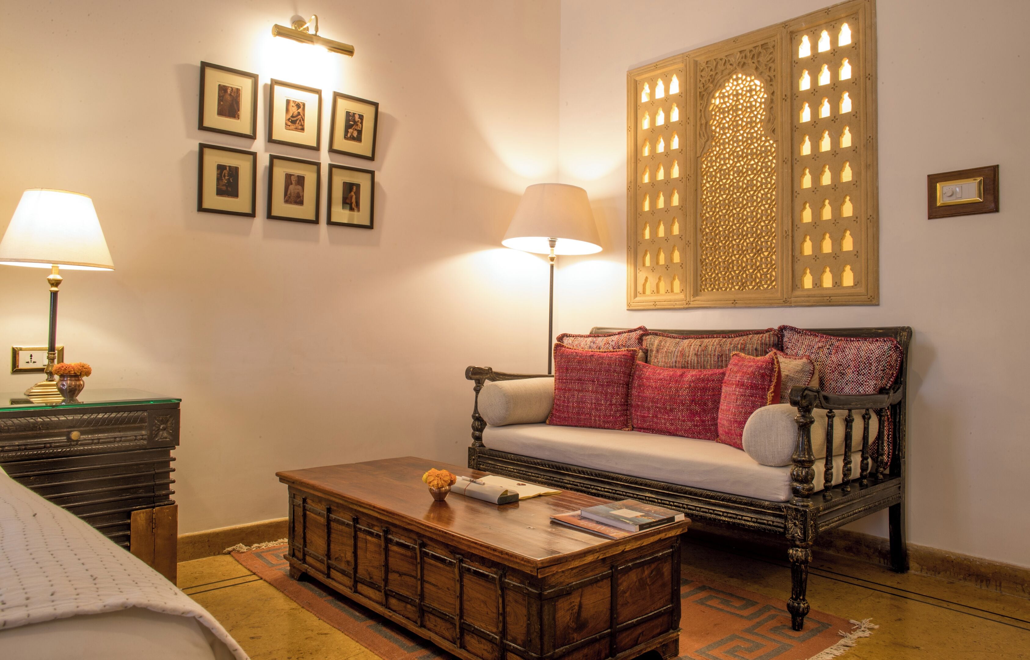 A cozy living room with a sofa, a coffee table, a lamp, and framed pictures on the wall.