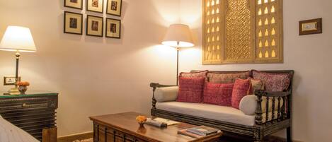 A cozy living room with a sofa, a coffee table, a lamp, and framed pictures on the wall.