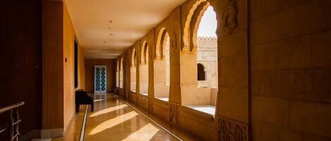 A corridor with arched windows and a piano.