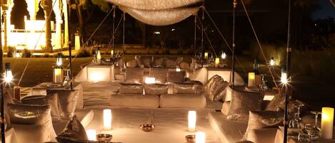 An outdoor dining area with tables, candles, and a canopy.