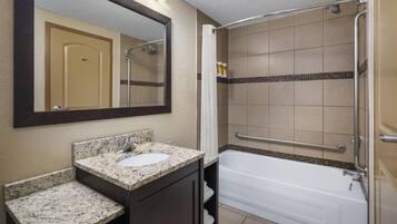 A bathroom with a sink, mirror, and bathtub.
