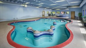 Una piscina interior con borde rojo, suelo de baldosas y techo con paneles azules.
