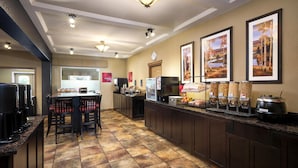 Cocina de hotel con una barra de buffet, que incluye una estación de café, un área de estar y varios recipientes de comida.